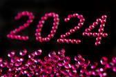 a new years eve party background for 2024 with pink sparkling jewels on a black backdrop