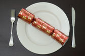 a modern christmas dinner table place setting with a cracker on a plate