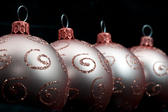 Oblique row of gold Christmas balls decorated with glitter curlicues for a dramatic seasonal background