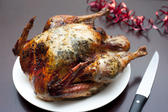 Whole roast festive Christmas turkey waiting to be carved for Christmas dinner with a carving knife alongside