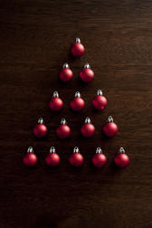 Christmas baubles tree shape with colorful red balls arranged in a triangle to resemble a modern Xmas tree over a dark background