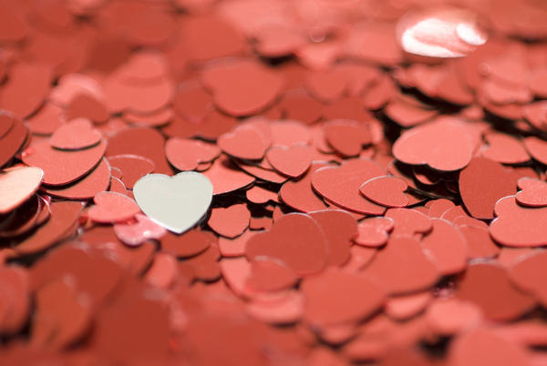 valentine concept: red metallic heart shaped confetti photographed with a narrow depth of field