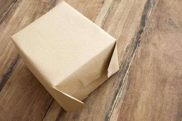 a small box partly wrapped in brown paper on a wood table