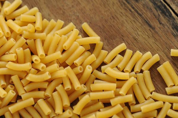 close up on pasta macaroni tubes on a wood surface