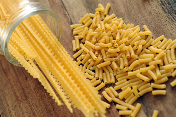 a selection of pasta including macaroni on a wood countertop