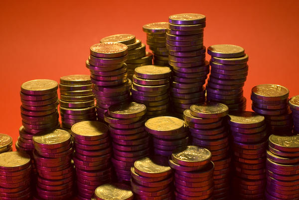 stacks of gold coloured coins on a red backdrop: money and financial concept